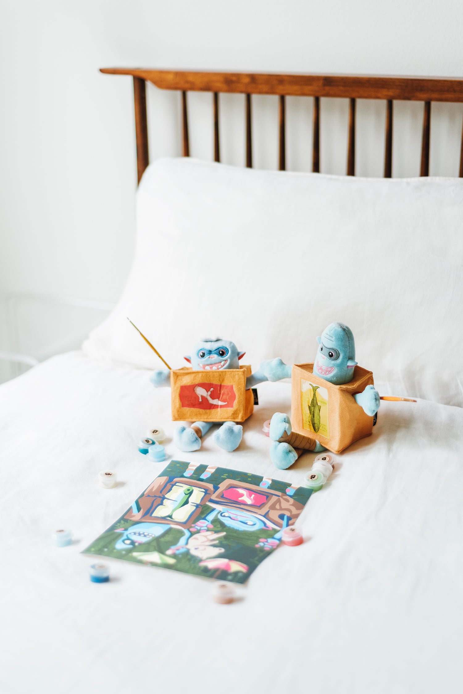 Fish and Shoe Boxtrolls sitting on a bed painting the Boxtrolls paint-by-number kit from Elle Crée x LAIKA Studios