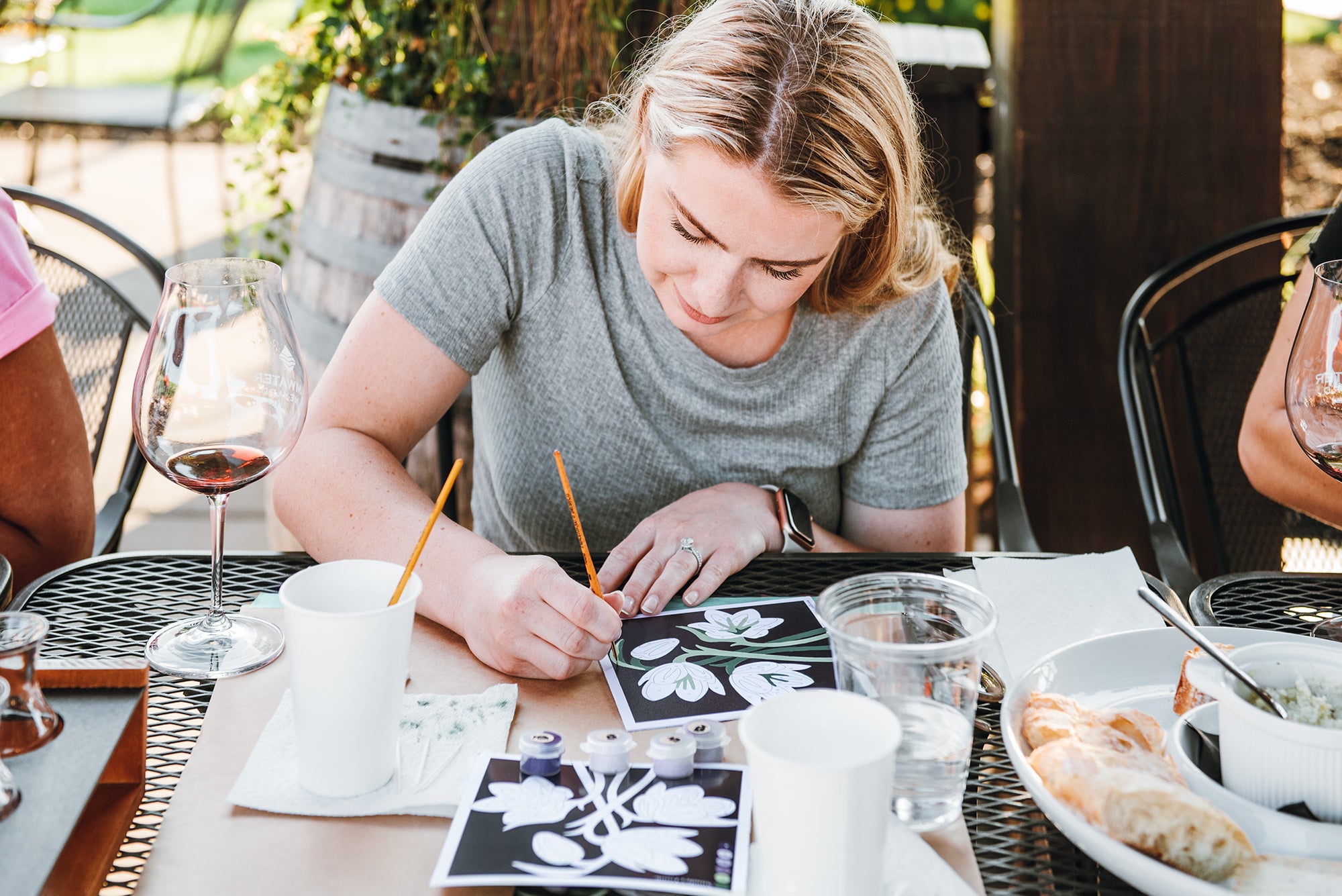 Woman's hands painting a purple flower (fritillaria flowers) paint-by-number mini kit at a paint-and-sip event at Tumwater Vineyard.