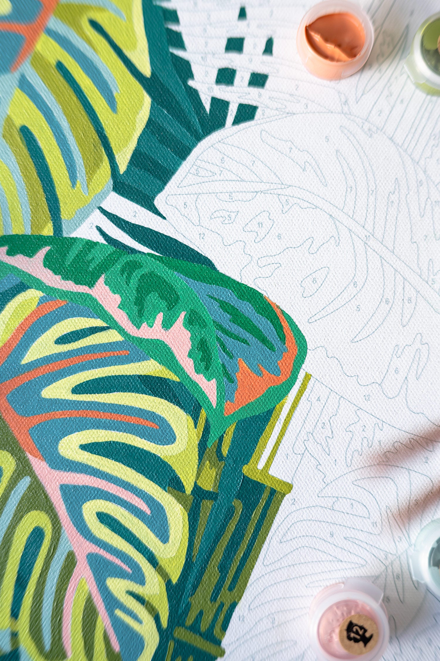Close-up of Vintage Verde paint-by-number kit in progress, featuring midcentury-inspired tropical leaves with Monstera, palm, and rubber plant designs.