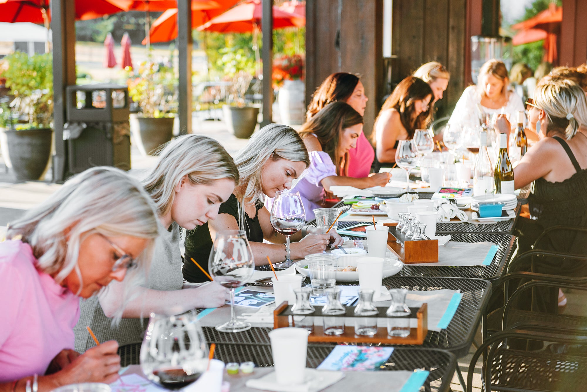 Women sitting at outdoor tables painting Elle Crée mini paint-by-number kits and drinking Tumwater Vineyard wine.